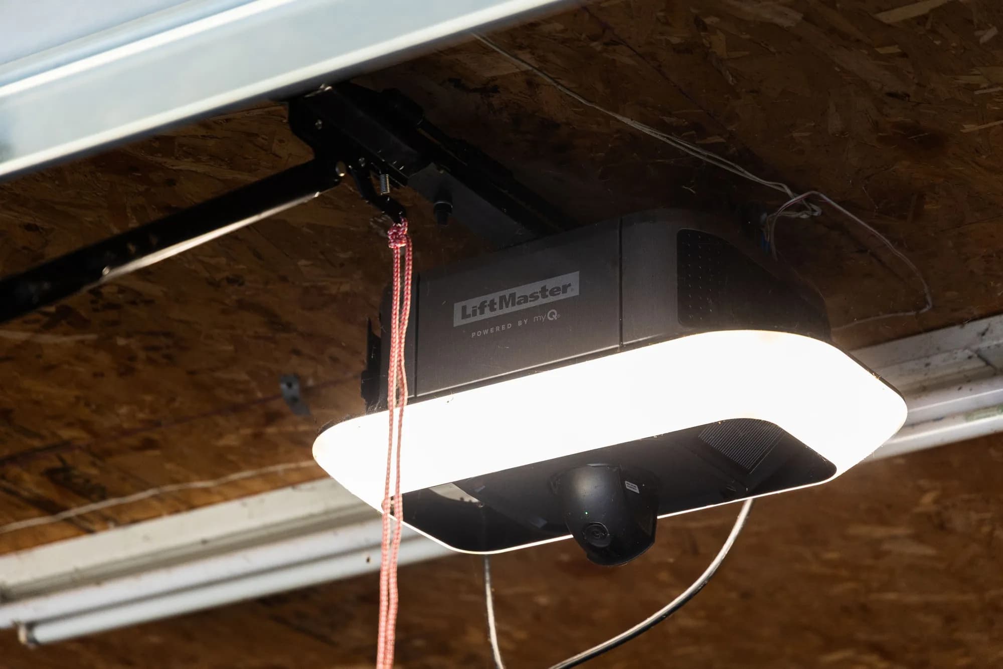LiftMaster ceiling-mounted garage door opener with its light on and the release cord hanging