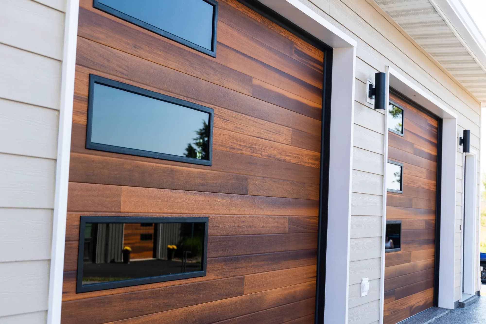 Cedar-tone horizontal plank garage doors with offset rectangular windows on a tan-sided home