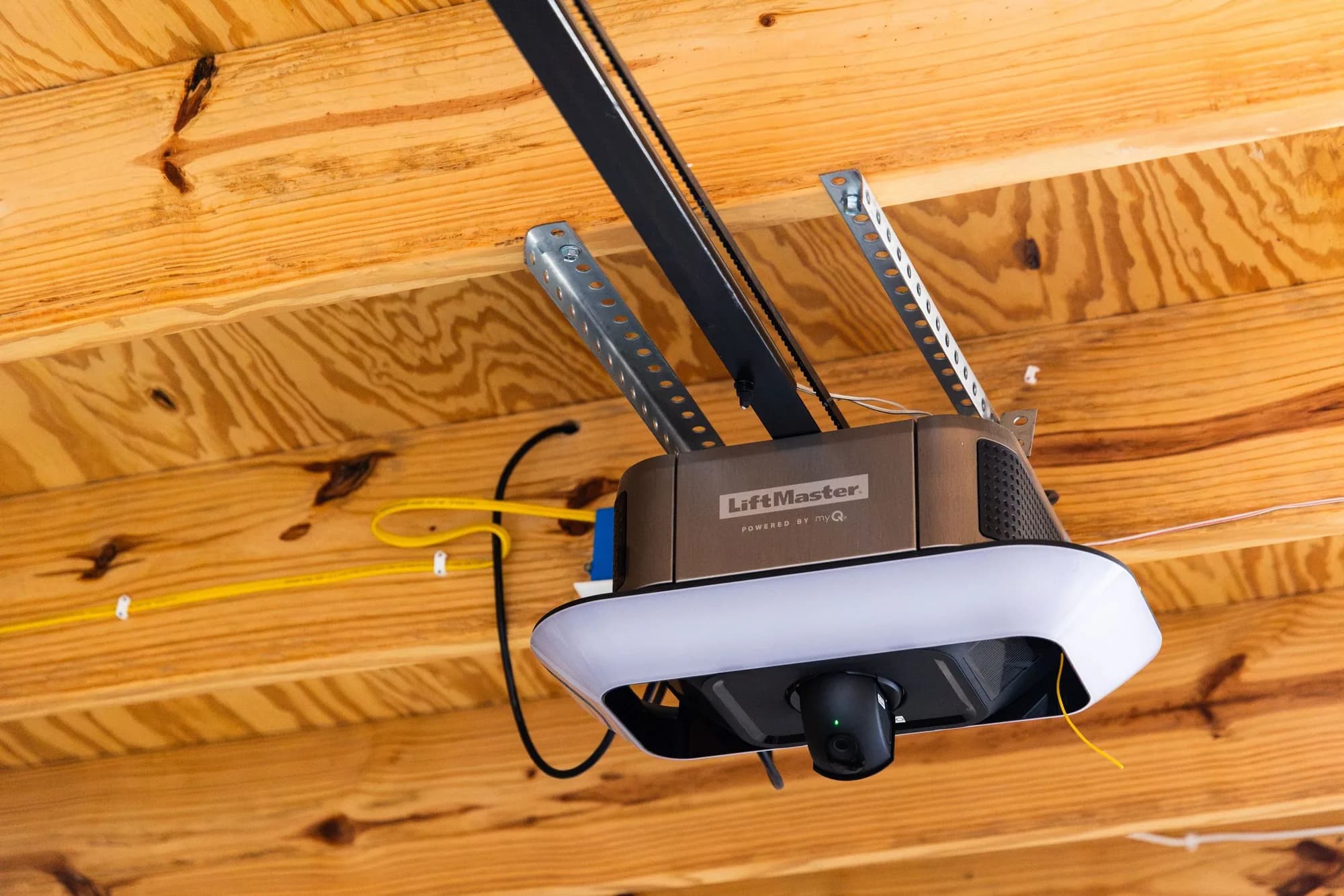 LiftMaster belt-drive garage door opener with its light on, mounted to a wood ceiling