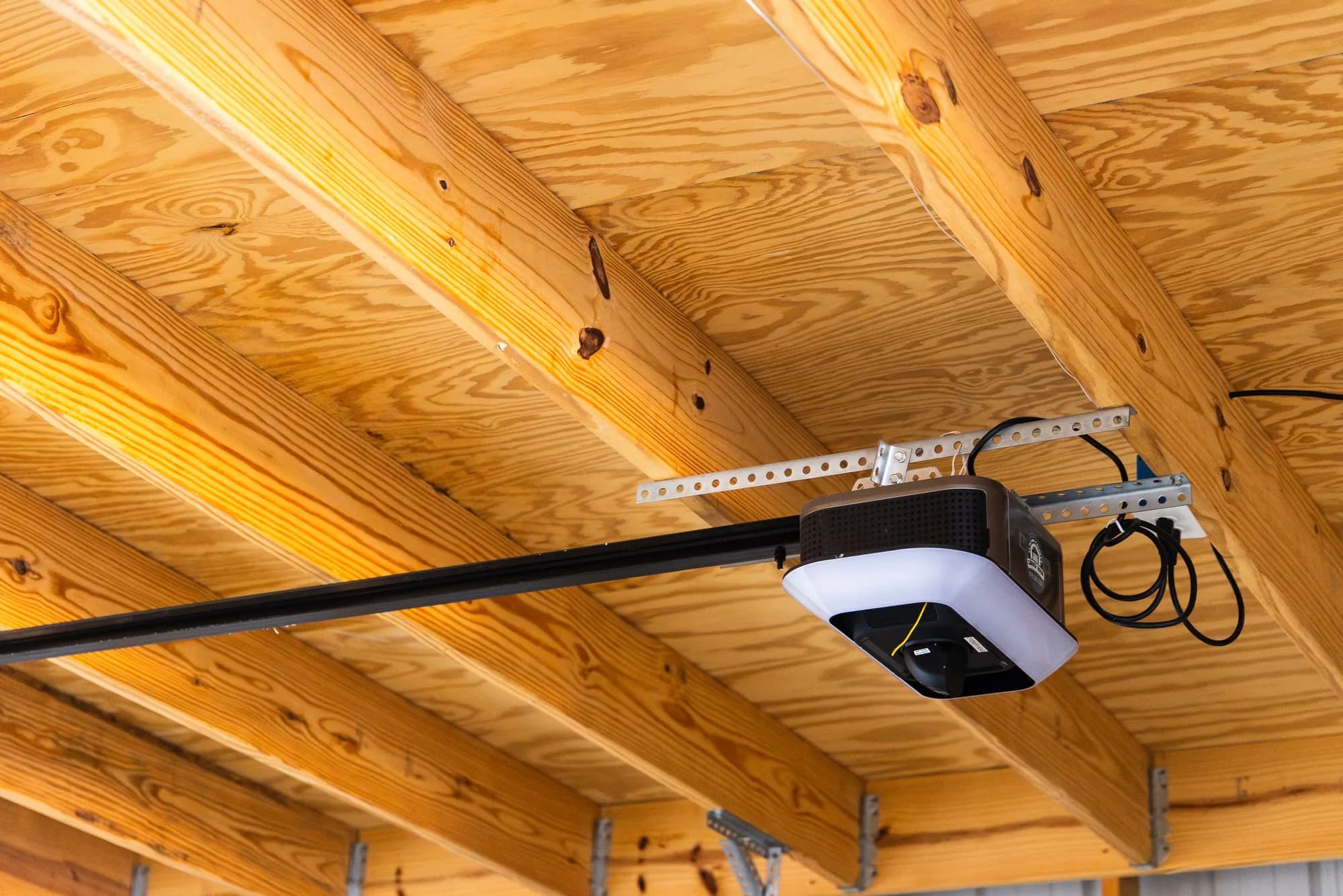 Belt-drive garage door opener with its rail mounted to a wood-framed garage ceiling