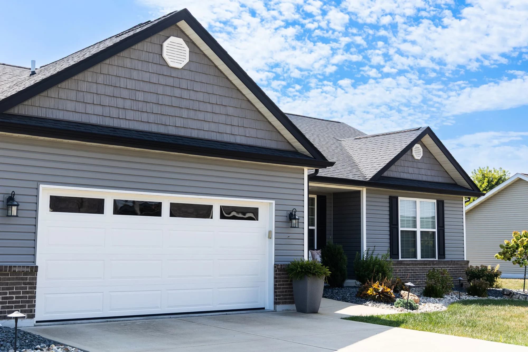White long-panel garage door with a row of top windows on a gray shake-sided house