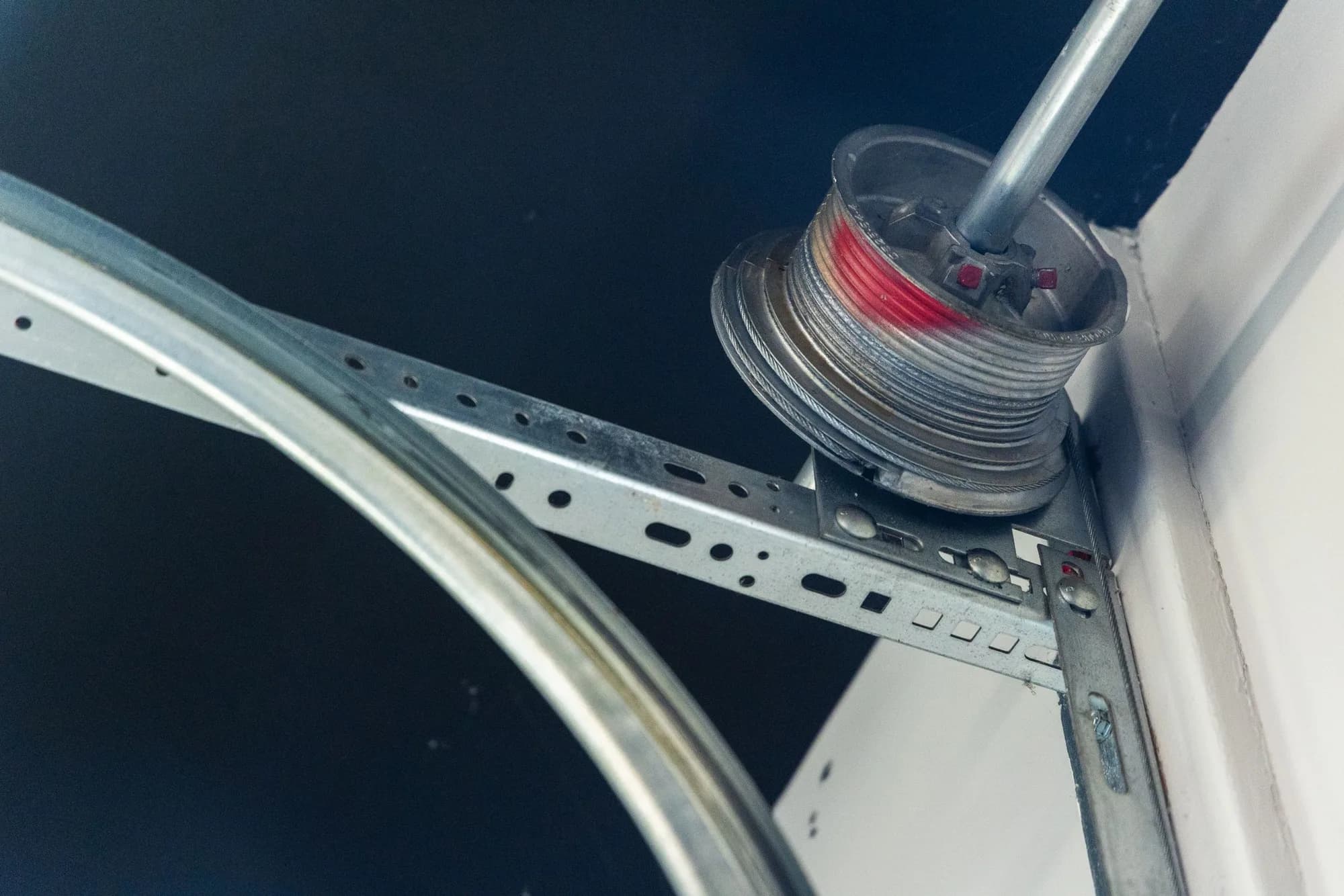 Garage door lift cable wound on its drum at the end of the torsion shaft above the vertical track