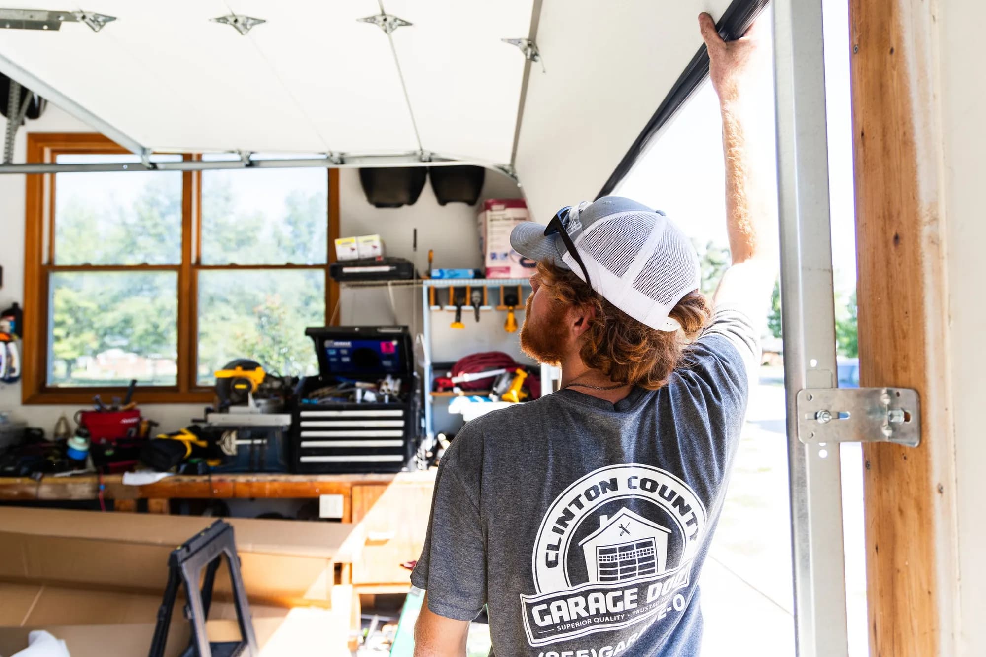 Technician adjusting the top bracket of a garage door from inside the garage