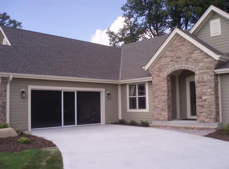 Garage opening on a tan-sided house closed in with a dark Lifestyle retractable screen, its passage door in the centre